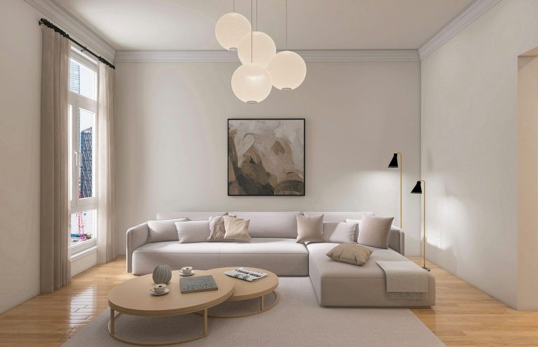 Salon moderne avec un canapé beige, table basse ronde et œuvres d'art sur les murs.