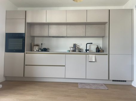 Cuisine moderne avec des meubles clairs, un four intégré et un plan de travail épuré.