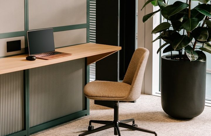 Bureau moderne avec un ordinateur, une chaise et une plante en pot.
