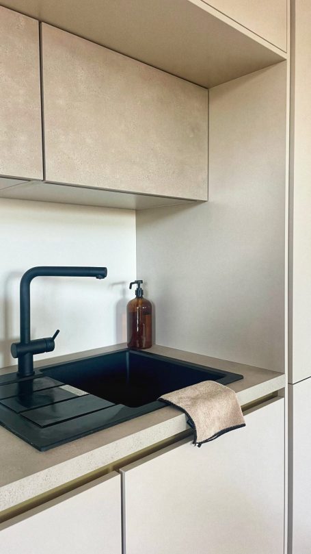 Évier moderne avec robinet noir et serviette beige sur le bord.